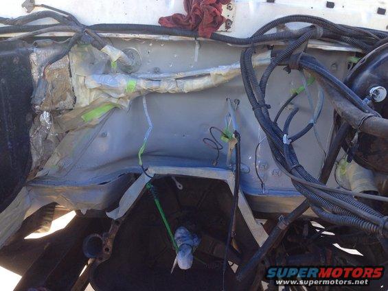 Engine bay with wiring harnesses and parts covered in tape and foil