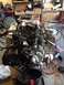 1978 Ford Bronco - Engine assembly with chrome valve covers and black belts on a stand in a garage.