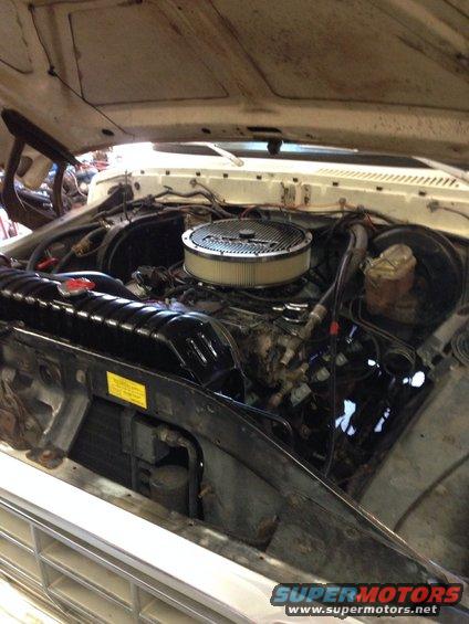 Engine bay with air filter, radiator, and brake fluid reservoir visible. Some wiring and hoses are present