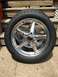 2004 Ford Crown Victoria - A single chrome wheel and tire assembly is shown, resting on a concrete surface with wooden steps in the background.