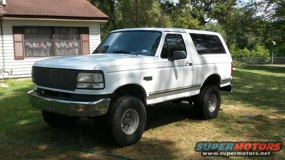 White Ford Bronco parked on grass in front of a house