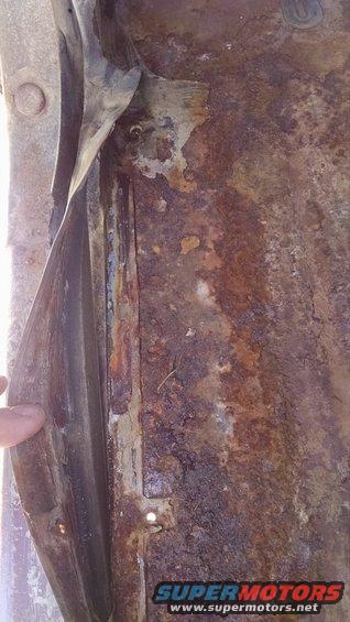 Rusted floor panel with peeling paint and visible metal corrosion