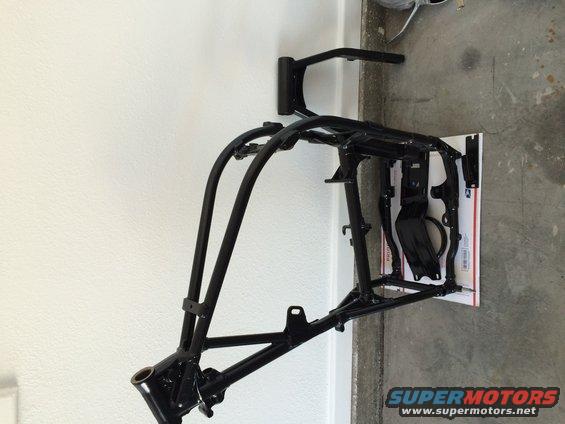 Black motorcycle frame, viewed from the side, mounted on a wall