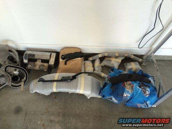 Motorcycle parts including fairing, exhaust, and frame components wrapped for storage