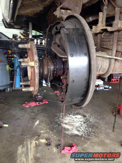 close-up of a vehicle's rear brake drum assembly with pads exposed, showing wear and grease