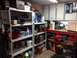 2004 Aston Martin Virage - A cluttered garage scene with storage shelves and a workbench filled with various items.