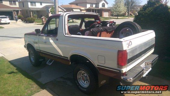 White and maroon Ford Bronco with a spare tire in the bed, parked on a driveway