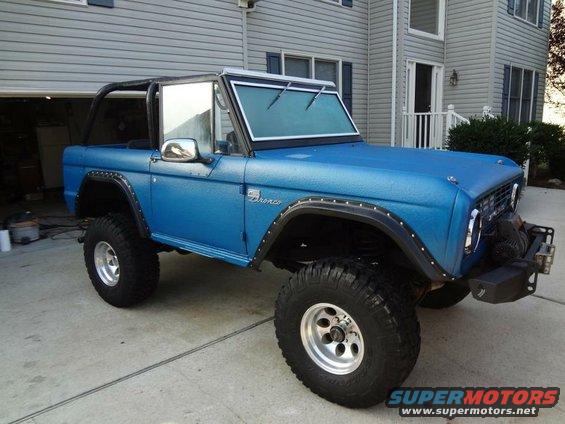 Blue Ford Bronco with aftermarket bumper and winch parked in a driveway