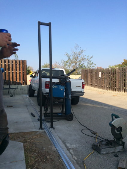 White pickup truck rear view, with welding equipment and a chop saw nearby