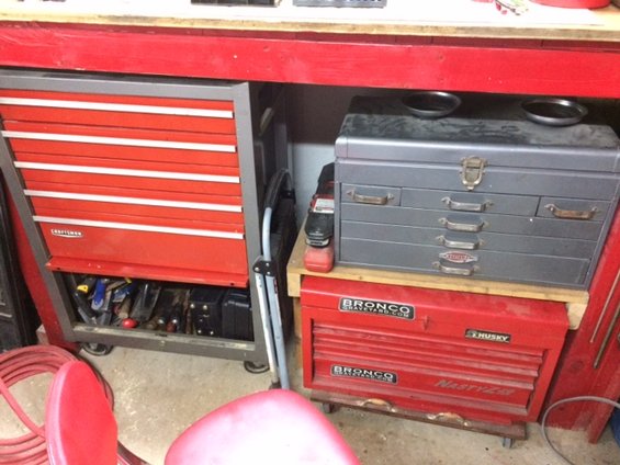 Red Craftsman tool chest with white drawers next to a gray metal toolbox and a red Husky tool chest