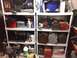 2004 Aston Martin Virage - A cluttered shelving unit displays a variety of items, including toolboxes, lanterns, and cleaning products.