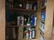 2004 Aston Martin Virage - A wooden shelving unit is stocked with a variety of cleaning supplies, automotive fluids, and manuals.