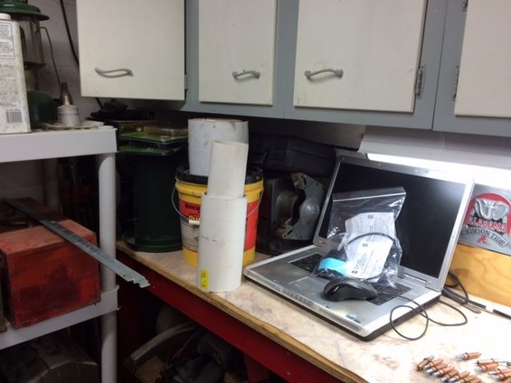 Laptop computer with mouse and plastic bag on a workbench with storage bins