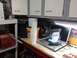 2004 Aston Martin Virage - A cluttered workbench displays a laptop, various containers, and other items, suggesting a workshop or storage area.