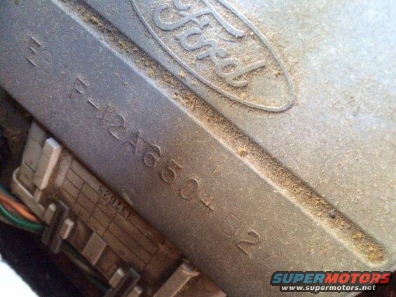 Close-up of a dusty metal Ford part with stamped serial number E2TF-12A650-B2 and wiring harness