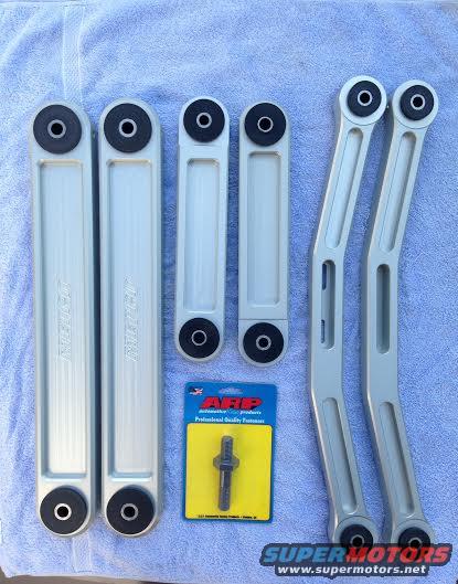 Four silver control arms and an ARP bolt kit on a blue towel