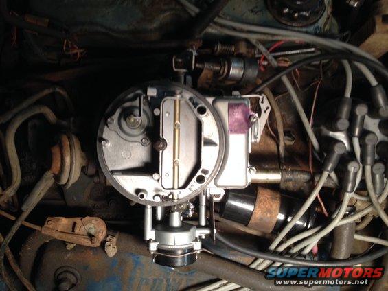 Carburetor and engine bay with wires and hoses visible