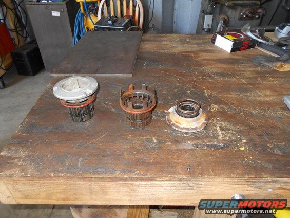Three automotive parts, likely hub assemblies, laid out on a wooden workbench