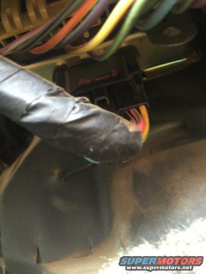 Wiring harness connector with orange and yellow wires, taped black loom