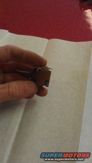 Hand holding a small, brown electrical component with metal contacts