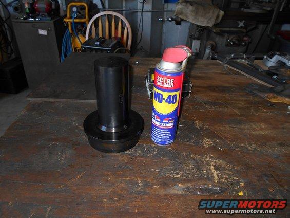metal cylindrical part with a base next to a can of WD-40 on a workbench