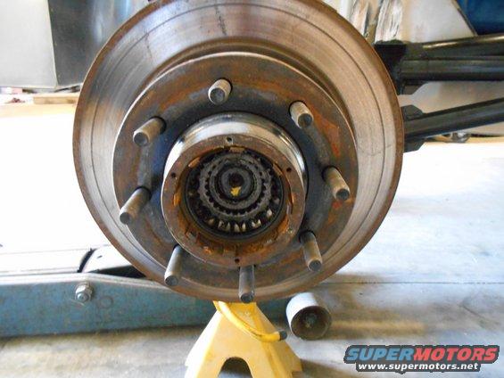 Rusty front wheel hub assembly with brake rotor, supported by a yellow jack stand