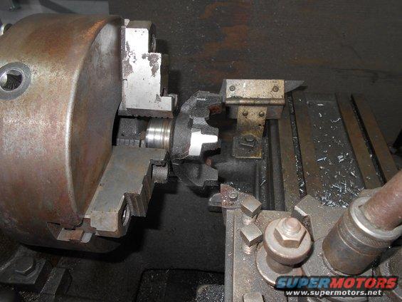 Metal gear being machined on a lathe with a chuck and cutting tool
