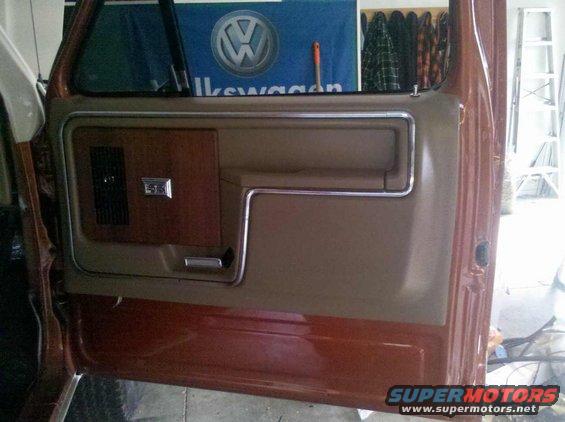 Brown and wood grain interior door panel with chrome trim