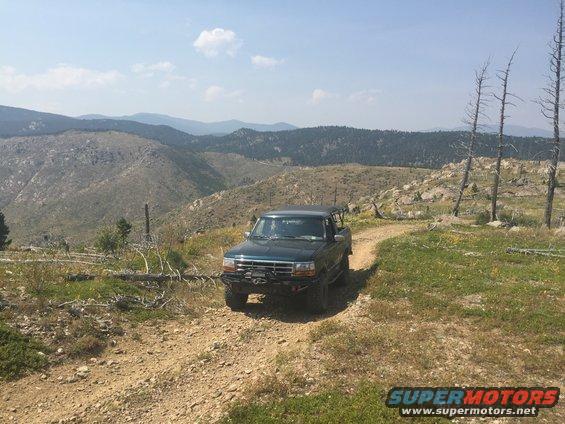 Dark green 1994 Ford Bronco on a dirt road with mountains in background