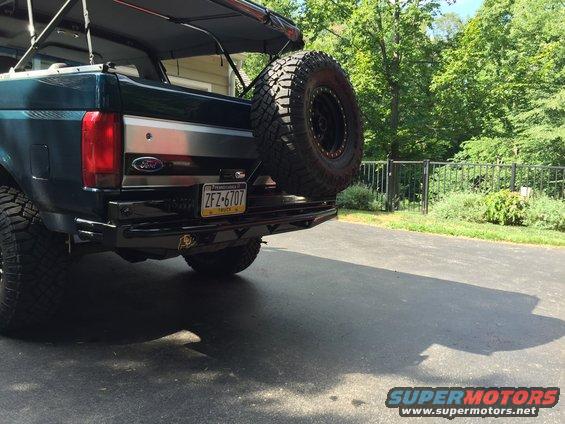 Rear view of a 1994 Ford Bronco with a spare tire mounted on the back. It has a custom bumper and a license plate reading ZFZ-6707