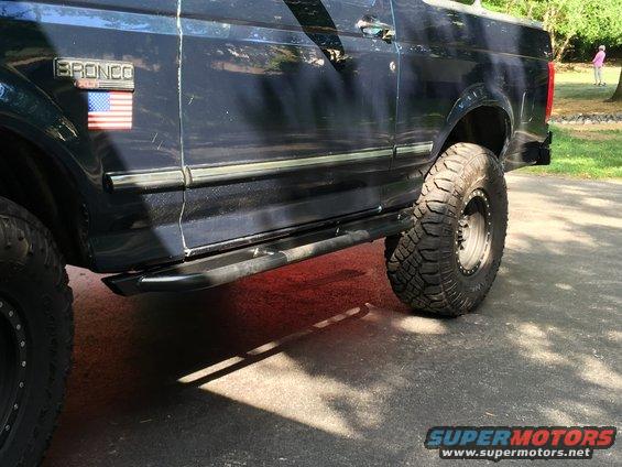 Dark blue 1994 Ford Bronco side view with American flag badge and large off-road tires
