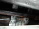 1978 Ford Bronco - Close-up view of the heavily rusted and coated undercarriage of a vehicle.