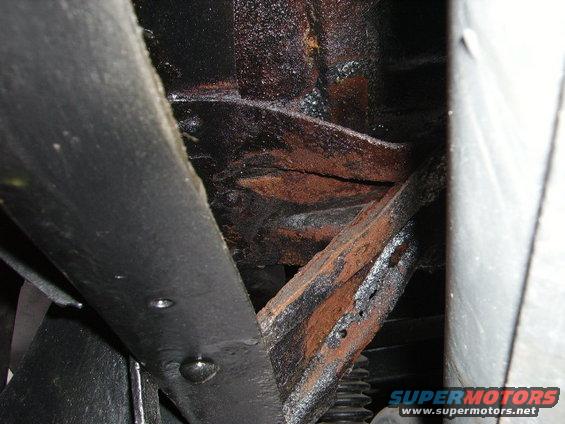 rusted frame components with black coating and some visible suspension parts
