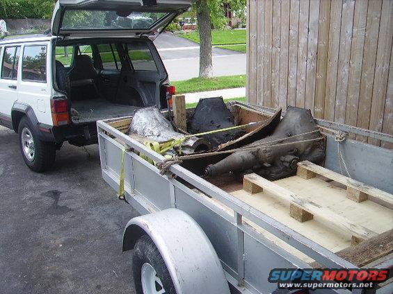 Jeep Cherokee parked next to a trailer loaded with transmission parts