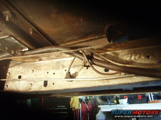 Underside of a vehicle frame with wiring and conduit visible