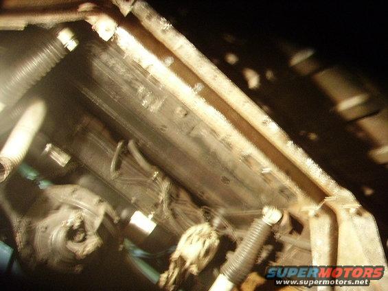 Undercarriage view of a vehicle, showing hoses, frame rails, and suspension components