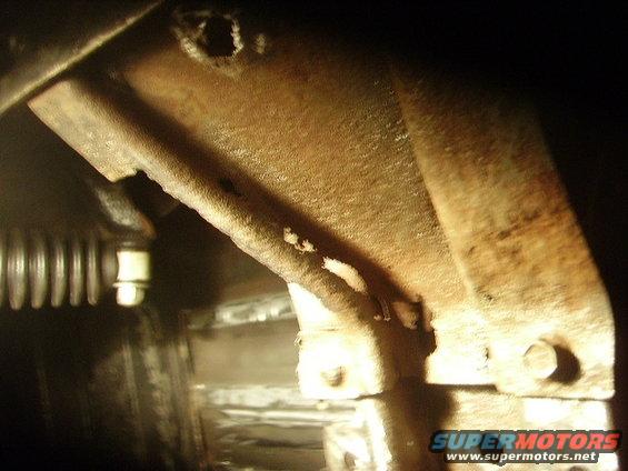 Rusted metal bracket with bolts and a ribbed hose
