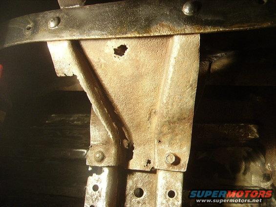 Close-up of rusted metal bracket and frame components with visible holes and bolts