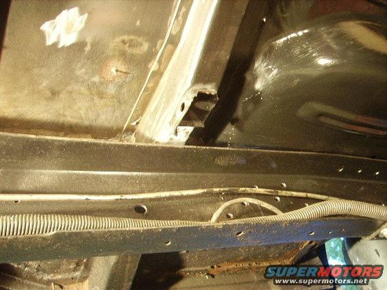 Underside view of vehicle frame with wiring harness and some rust