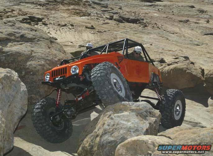Orange rock crawler with large tires navigating rocky terrain