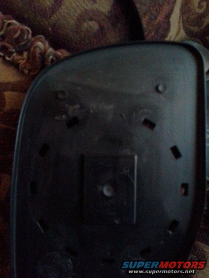 Back of a black car side mirror with mounting holes and a central square attachment point