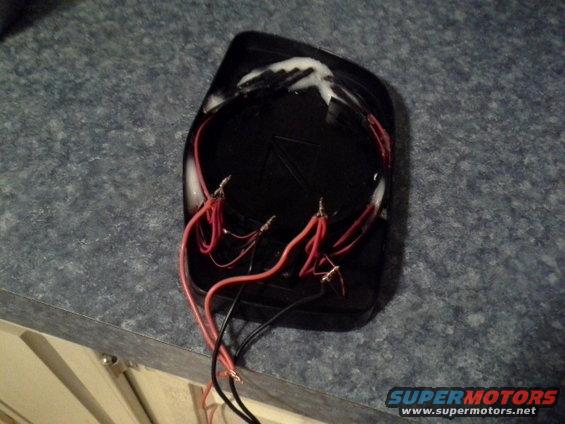 Modified side mirror with exposed red and black wires attached to terminals