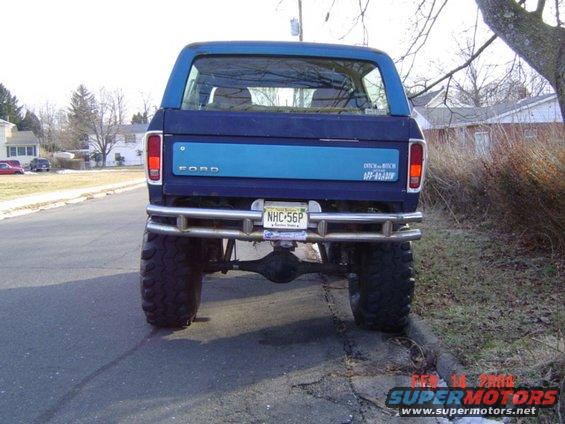 Rear view of blue Ford Bronco with large tires and custom metal bumper. License plate NHC-56P