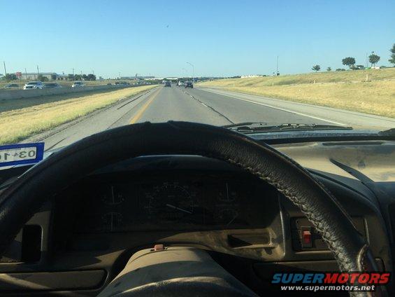 View from driver's seat looking at highway, dashboard and steering wheel visible