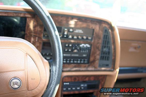 1991 Buick Reatta interior showing woodgrain dashboard, radio, and steering wheel with R logo