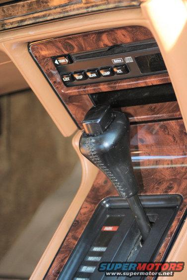Car interior showing woodgrain trim, a gear shifter, and a radio/CD player. The trim has a glossy finish