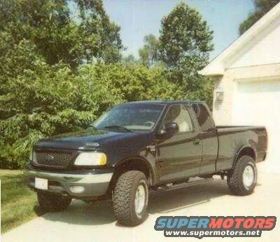 Black Ford F-150 pickup truck, 3/4 front view, lifted suspension, parked in driveway