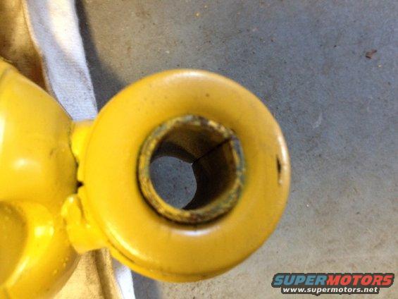 Yellow shock absorber end with visible wear and a Supermotors.net watermark