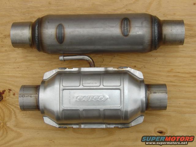 Two metal exhaust components, one labeled CATCO, on a wooden surface