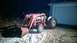 1959 Ford Pickup - A red tractor with a front loader is parked on a dirt surface in front of a closed garage door.